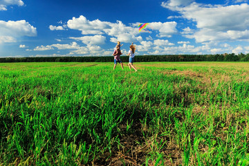 Mother, father and daughter are flying a kite in the field.