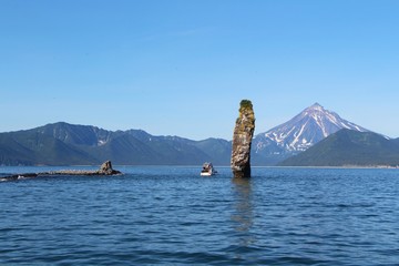 Rocky reef in the waters of the Pacific Ocean off the coast of Kamchatka, Russia. Vilyuchinsky volcano (also called Vilyuchik) is visible in the background.