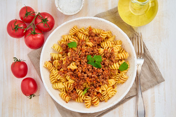 Bolognese pasta. Fusilli with tomato sauce, ground minced beef. Traditional italian cuisine. White wooden table. Top view.