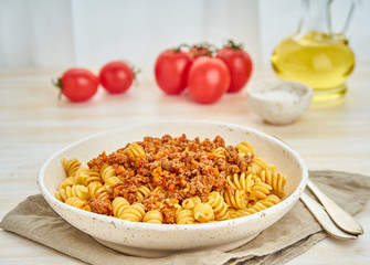 Bolognese pasta. Fusilli with tomato sauce, ground minced beef. Traditional italian cuisine. White wooden table. Side view.