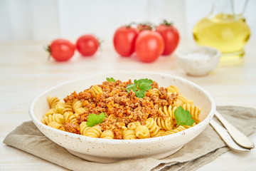 Bolognese pasta. Fusilli with tomato sauce, ground minced beef. Traditional italian cuisine. White wooden table. Side view.