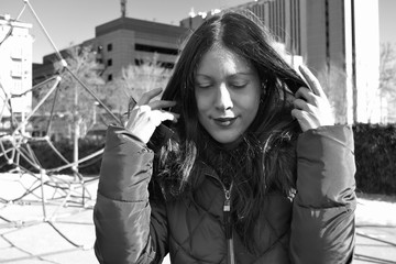 Portrait of a beautiful young woman with a coat on modern urban background. Black and white.