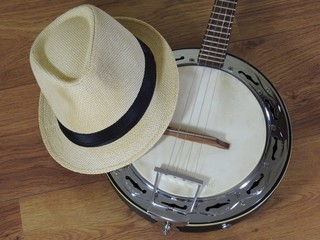 A samba banjo (a Brazilian string musical instrument) and a samba player (sambista) hat on a wooden surface. The instrument is widely used to accompany samba, the most popular Brazilian rhythm.
