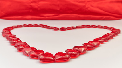 Obraz premium Heart shaped lined from small glass red hearts on a white and red background. Valentine's Day. Love symbol