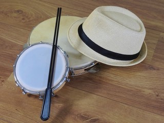 A samba player (sambista) hat and two Brazilian percussion musical instruments: pandeiro (tambourine) and tamborim with drumstick. The instruments are widely used to accompany samba music.