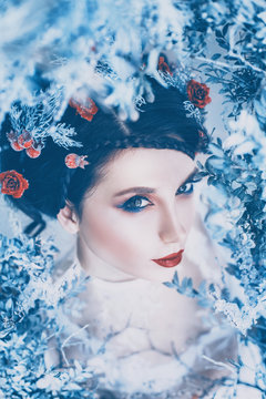proud majestic queen of winter and eternal cold in long white dress with dark collected hair adorned with frozen roses and berries, a gorgeous girl in the ice kingdom, a gloomy image in bright colors