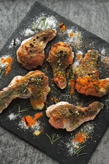 Raw glazed chicken wings marinate with spices on a stone board.
