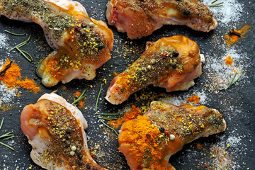 Raw glazed chicken wings marinate with spices on a stone board.