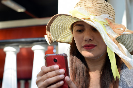 Beautiful Face Of Middle Age Woman Wearing Sunday Hat Browsing Internet With Smart Phone. Close Up