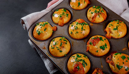 close-up of homemade mini bun topped with mushrooms and meat cheese, garlic and herbs on dark background, near clove garlic