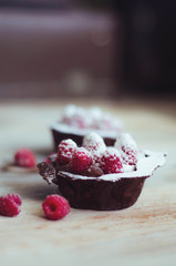 Delicious chocolate cakes with coffee mousse and raspberries on a white table decorated with icing