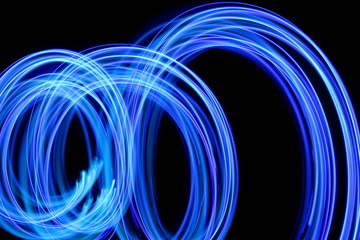 Blue light painting photography, long exposure, blue streaks of vibrant color against a black...