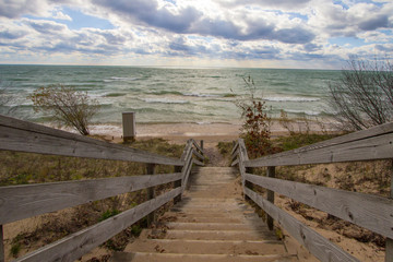 Obraz premium Wooden Stairs To Beach. Long wooden staircase leads to a sunny sandy beach on the Michigan coast of Lake Michigan.