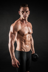 Athletic shirtless young male fitness model with dumbbells