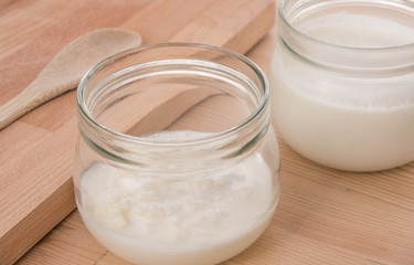 Organic Kefir and kefir grains in glass jars with wooden board and spoon