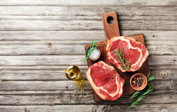 Fresh Meat On Wooden Cutting Board Top View. Raw Beef Steak And Spices For Cooking.