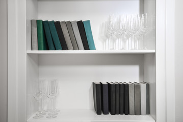 collection of books/ Interior details of a rich office. A collection of books on a white shelf and champagne glasses
