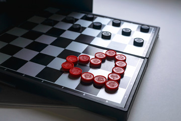 Chess Board lined with red checkers in the form of a heart. Valentine's day card concept. Heart on Valentine's day background