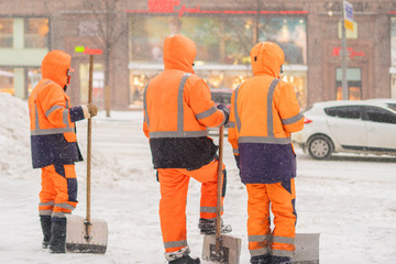 groop of city janitors stand in snowy street