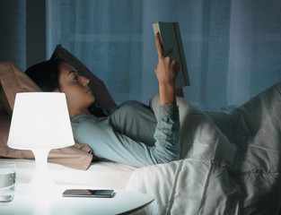 Woman reading a book at night