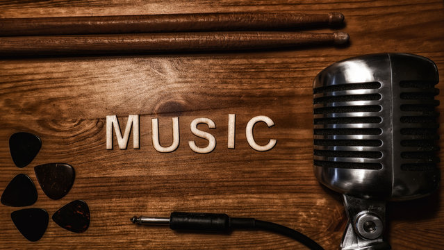 Wooden letters spelling out music, animated using stop motion. Bordered by  music gear including a vintage style microphone, guitar picks, drum sticks  and an instrument cable. Stock Photo | Adobe Stock