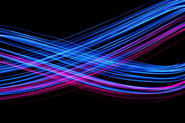 Long exposure, light painting photography.  Vibrant electric blue and neon pink streaks of colour against a black background