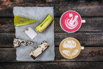 Top view latte art with two kinds of cheesecake on wooden table, coffee shop background. With the copy space for your logo.