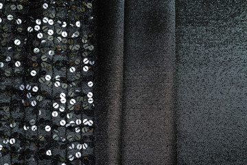 Parallel folds of black shiny fabric with sequin trim