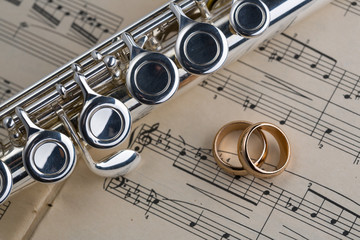 Obraz premium Wedding rings with Flute on old notes background for graphic and web design, Modern background. Internet concept. Trendy background for website design or mobile app
