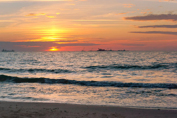 Fototapeta premium Sunset over the sea. Reflection of sunlight in the sea waves. Red and yellow sky in the rays of the sunset.