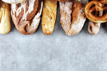 Foto op Plexiglas Bakkerij Assortiment van gebakken brood en broodjes op stenen tafel achtergrond