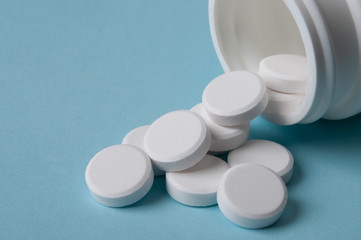 white pills spilling out of the medicine bottle; health care and medical treatment concept