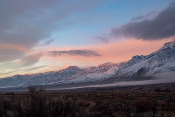 pink sky clouds over snowy mountain range at sunrise