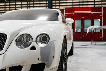 Auto body repair series: White luxury car in garage, bumper repaint job