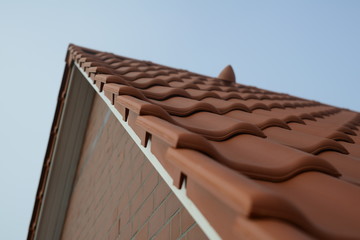 Weißer Ortgang aus Holz vom Zimmermann mit neuen roten Dach Ziegeln und Dunstrohr Dach Entlüfter vom Dachdecker als fertige Arbeit beim Hausbau