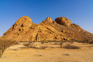 Fototapeta na wymiar Dramatic rock formation with interesting lines and shapes and golden sunlight at dawn Spitzkoppe, Damaraland, Namib Desert, Namibia.
