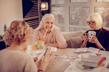 Happy aged woman trying a tasty cookie