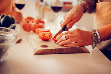 Selective focus of a ripe tomato being cut for salad
