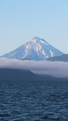 View of Vilyuchinsky volcano (also called Vilyuchik) from tourist boat. The cloud lies on the coastal cliffs. Vilyuchinsky is a stratovolcano in the southern part of Kamchatka Peninsula, Russia.