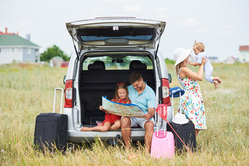 Vacation, Travel - family ready for the travel for summer vacation. suitcases and car route. People with map in hands planning road trip. travel concept. traveler. 