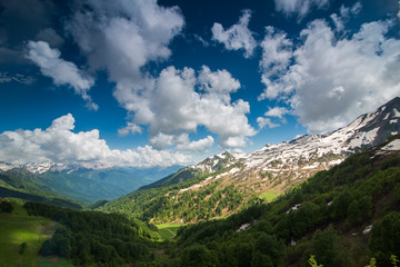 Obraz premium a mountain range under a cloudy sky with bursting sunbeams and shadows on the ground