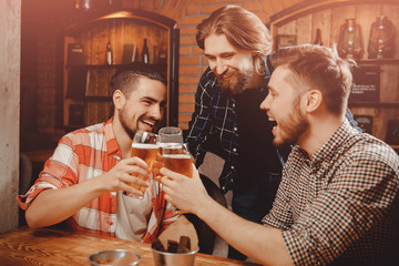 Old friends are happy and funny men with glasses of beer clink bar