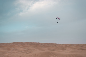 Fototapeta na wymiar The paramotor flies over sandy dunes in the Sahara desert, incredible experience in Africa
