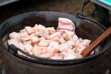 fresh traditional pork cracklings are cooked in the cauldron outside