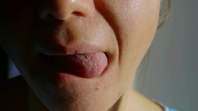 woman is sticking out her tongue and rotating it around mouth, close-up view of part of face