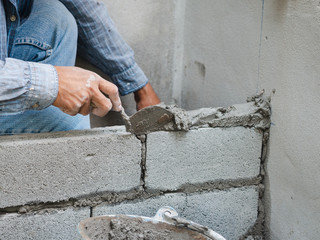 professional construction worker laying bricks with cement.