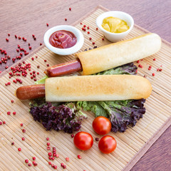 Hot dog with grilled sausage, ketchup, mustard, lettuce and tomatos. Traditional american fast food.
