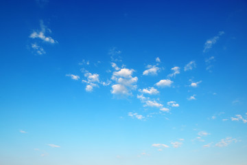 Naklejka na ściany i meble Small fluffy clouds on bright blue sky