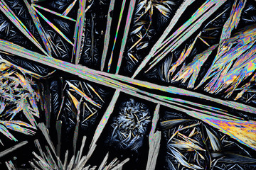 Photo through a microscope of crystals grown from a solution of benzoic acid in alcohol. Polarized...