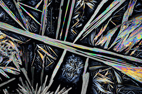 Photo through a microscope of crystals grown from a solution of benzoic acid in alcohol. Polarized light technology.